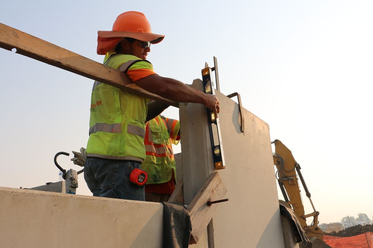 A construction worker holds a level against a precast concrete wall panel to check that it is plumb.
